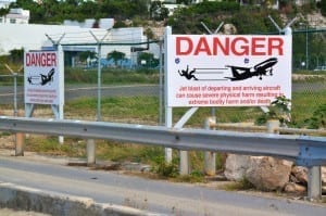Placas alertando aos pedestres que tomem cuidado com os aviões decolando
