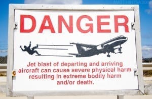 Placas alertando aos pedestres que tomem cuidado com os aviões decolando