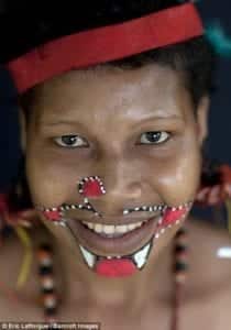 Confortável diante da câmera, a mulher sorri enquanto se prepara para um ritual em Trobriand Island, Papua Nova Guiné