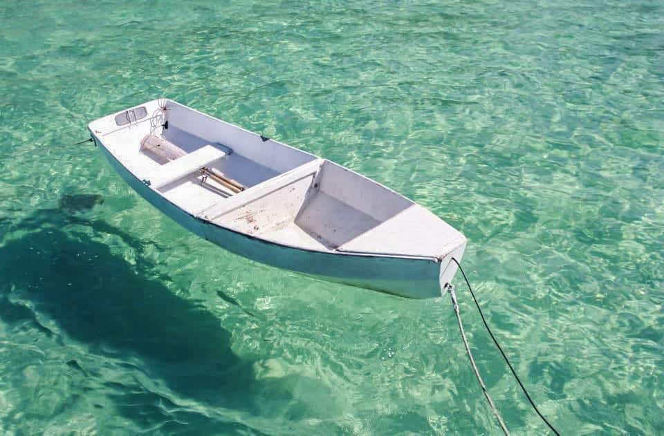 O barquinho parece flutuar nas águas cristalinas de Jaw's Beach, em Nassau, capital das Bahamas