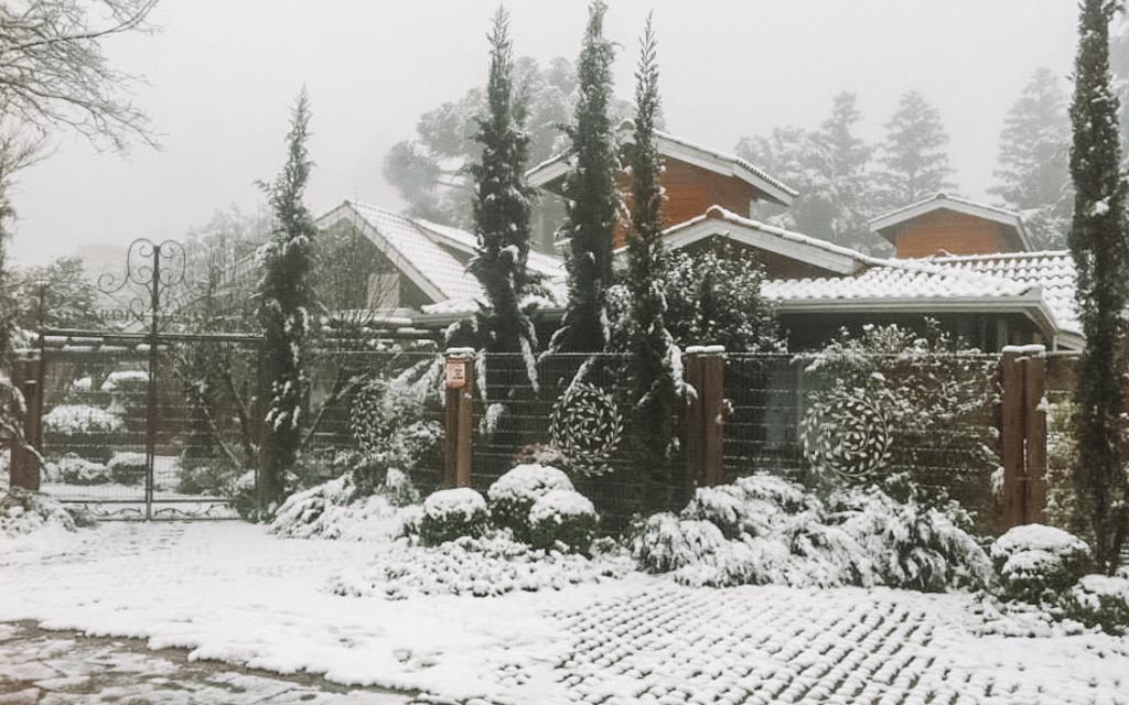 Fachada da Pousada Jardim Secreto em dia de neve em Gramado